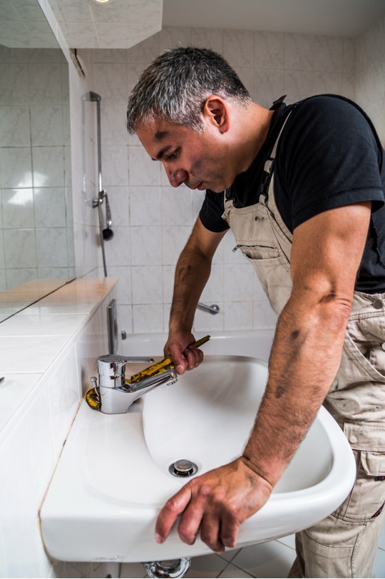 Plombier cherche la panne sur un robinet de lavabo