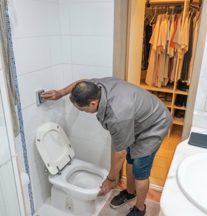 Plombier teste le fonctionnement d'une chasse d'eau chez un client